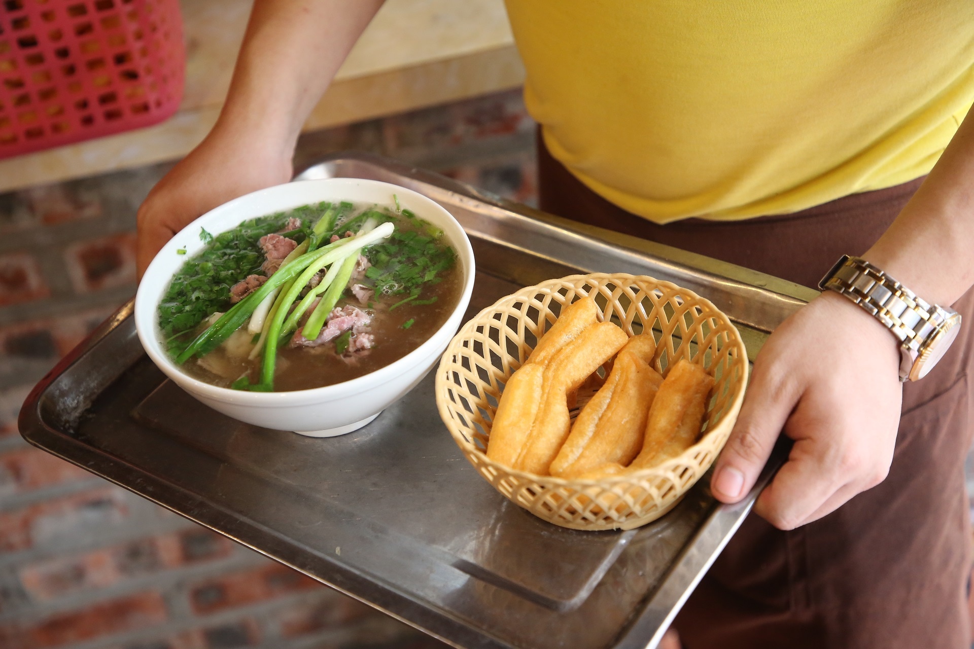 Pho is a traditional dish, featuring steaming hot broth, fresh beef, and crispy fried dough sticks served alongside
